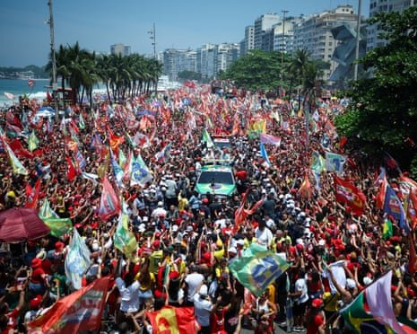 A huge crowd waving flags surrounds Lula's vehicle at a Copacabana campaign rally.