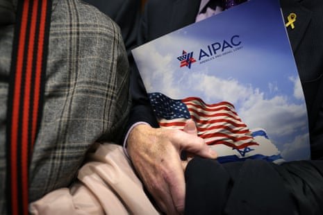 A visitor's hand holds an AIPAC folder showing American and Israeli flags