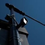 A license plate reader camera is mounted on a utility pole against a clear blue sky