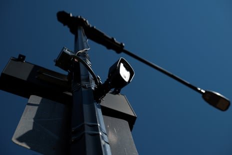 A license plate reader camera is mounted on a utility pole against a clear blue sky