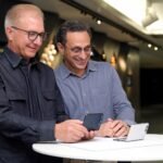 Greg Joswiak, Apple’s senior vice president of Worldwide Marketing, and Kenny Gersh, MLB’s executive vice president of Media, Business Development, and Product, using the MLB app on iPhone Duo.